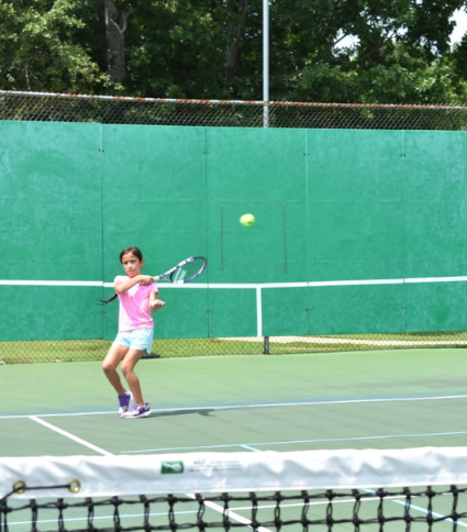 girl hitting forehand in front backboard