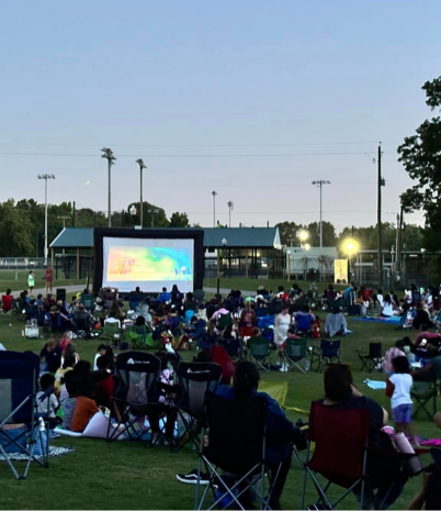 People gather in Pelham City Park to watch a movie at dusk.