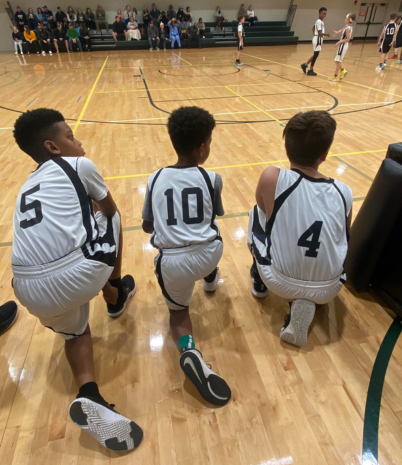 Boys kneeling on the sidelines of a basketball game