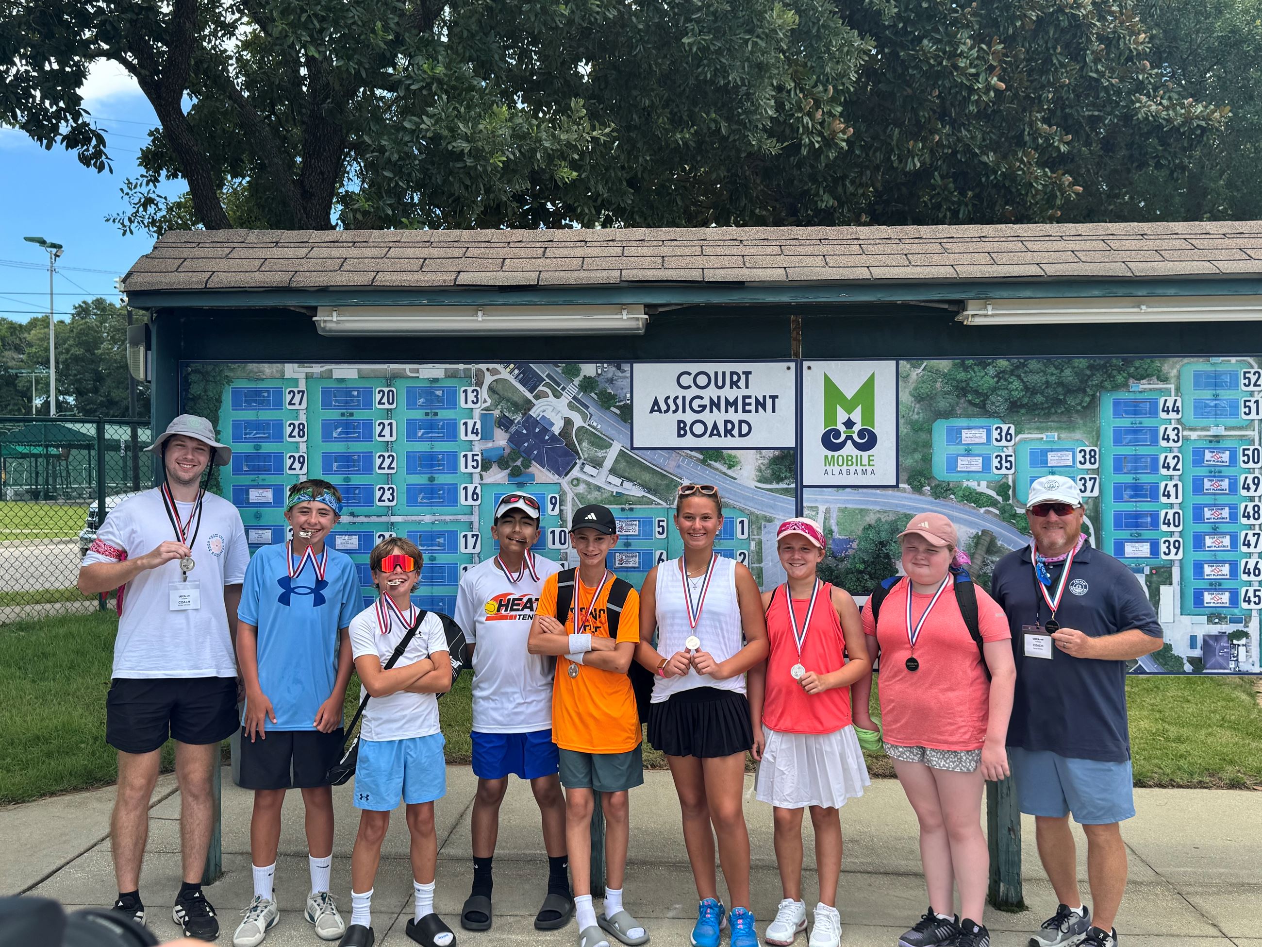Jr Tennis Players standing in a line holding medals